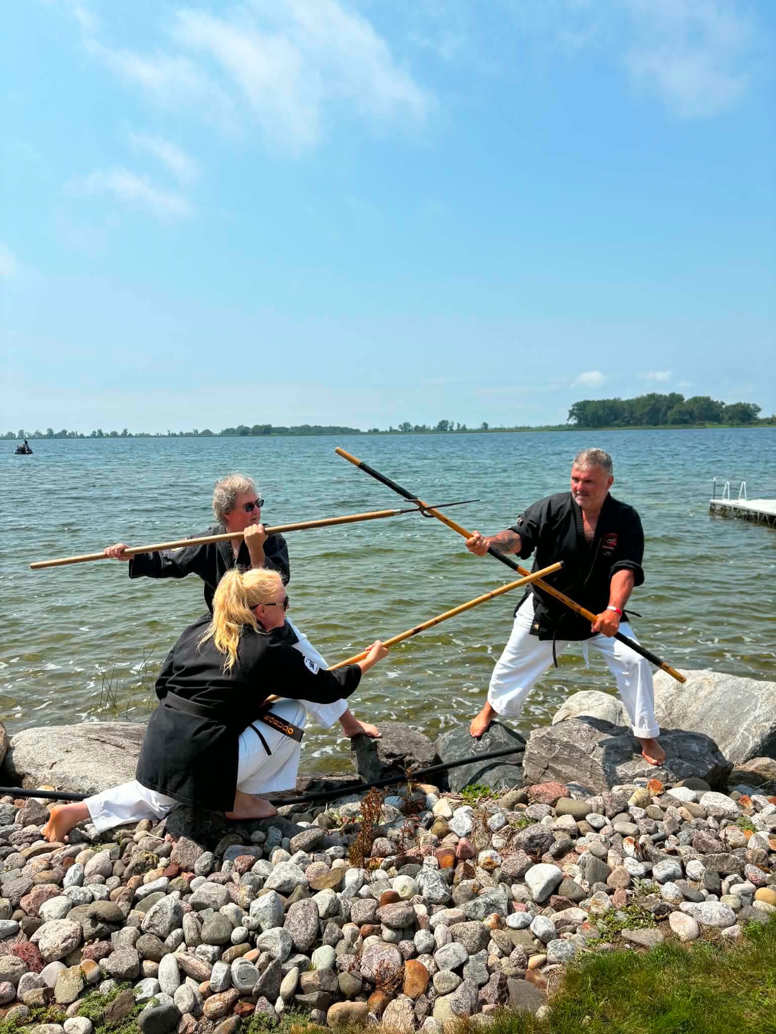 Trois pratiquants kobudo en confrontation d'armes sur les rochers